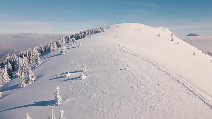 Winter mountains in frozen Carpathian nature with hiking trail on snowy hill Aerial view tourism background