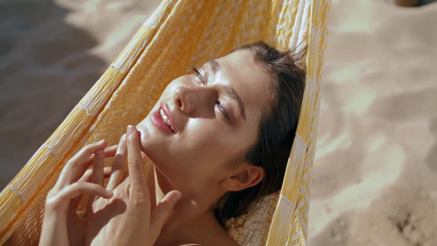 Beach girl resting sunlight hanging in hammock closeup. Happy woman chilling enjoying summer vacation at sandy ocean shore. Calm smiling girlfriend daydreaming in bikini. Idyllic seaside leisure  | Shutterstock HD Video #1100703339