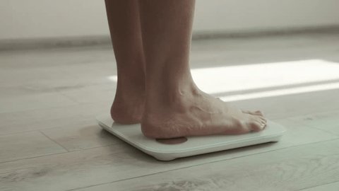 Woman walking in body weighing scale. Daily weight measurement, female legs stand on digital smart scales, close-up. Barefooted woman. healthy lifestyle. smart scales, fitness, workout, diet, weight วิดีโอสต็อก
