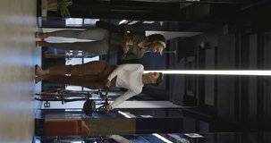 Vertical video of happy diverse business people discussing work and walking at office. Work at a modern office.