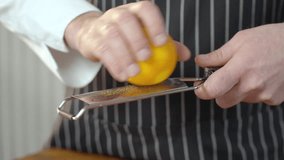 The cook grates the orange peel. Mans Hands Doing Spice From Orange Peel. Slow motion video.