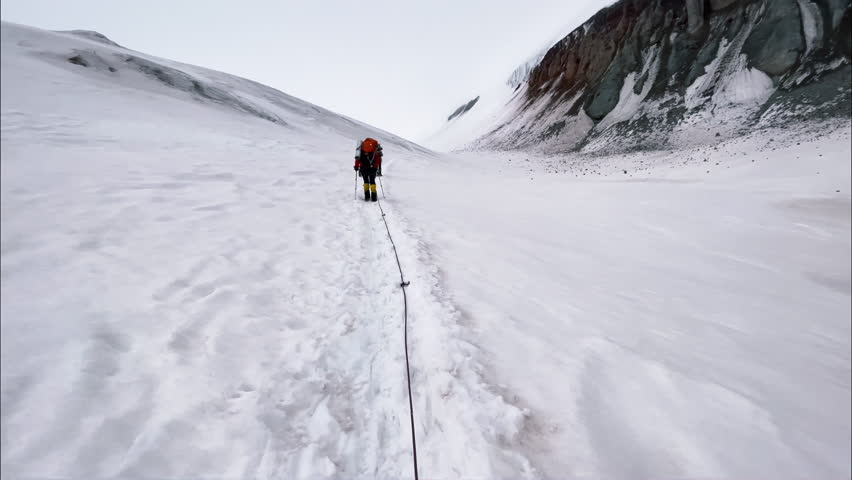 4K footage of alpinists in winter climbing clothes linked with rope walking slowly together towards top of mountain. Kazbek (Kazbegi) 5054m. Climbing, alpinism, winter sports, extreme sport concept. Royalty-Free Stock Footage #1100708393