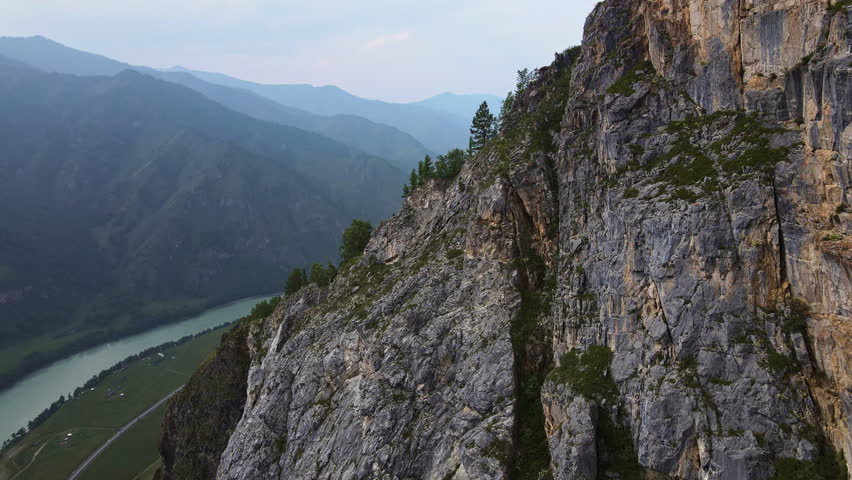 Aerial view of the turquoise mountain river Katun in Altai. Island in the middle of the river. The slopes of the ridges in the valley are covered with forest. Movement of the camera from behind a rock Royalty-Free Stock Footage #1100709127