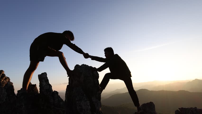 Silhouette of two tourists lends helping hand climb cliffs mountains helping hand. teamwork helping hand business travel silhouette concept.  teamwork people climbers climb top overcoming hardships. | Shutterstock HD Video #1100714781