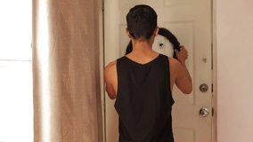 Young latin man hanging a spooky halloween wreath to decorate his home. Medium shot. 
 - Powered by Shutterstock - Get 15% off with code: PIKWIZARD15