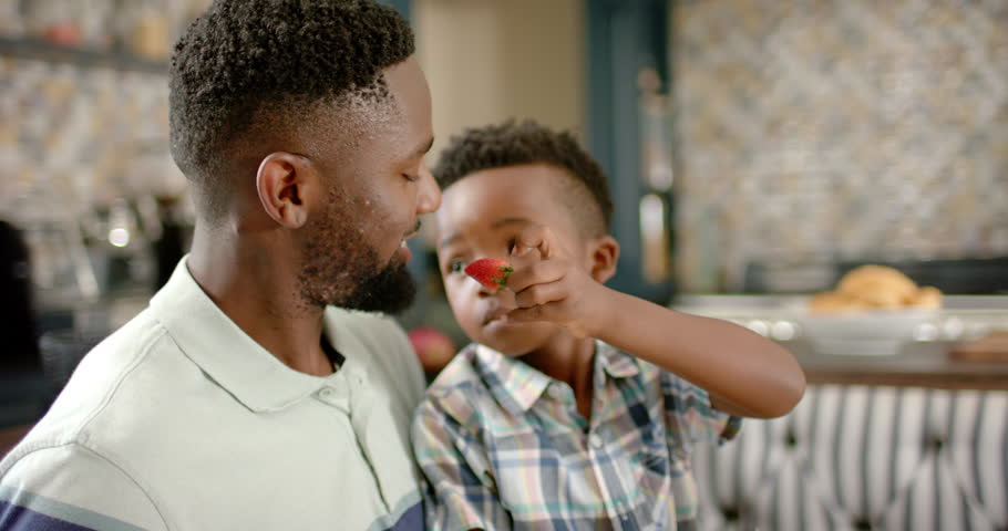 Happy african american father and son having breakfast, in slow motion. Spending quality time at home concept. | Shutterstock HD Video #1100719851