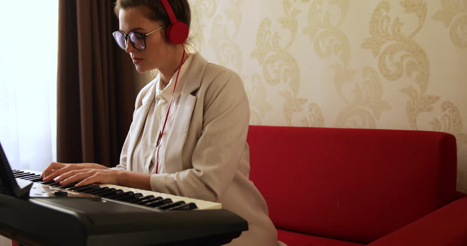 Young woman playing synthesizer at home