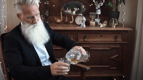 Stylish bearded senior man with a glass of whiskey