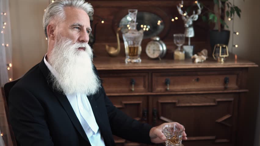 Stylish bearded senior man with a glass of whiskey