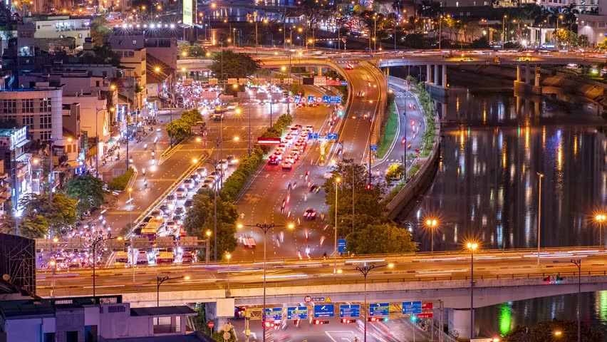 Night High Wide shot of busy motorway lanes with heavy traffic passing by the Saigon river, Vietnam, Ho Chi Minh City