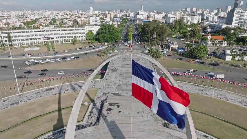 Flag waving in the wind on triumphal arch, Plaza de la Bandera at Santo Domingo city. Aerial drone view