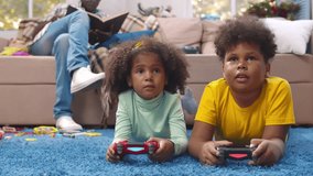 African-American father babysit children playing video game. Boy and girl play video game with joystick. Happy siblings playing computer game with console and having fun. Realtime.  - Powered by Shutterstock - Get 15% off with code: PIKWIZARD15
