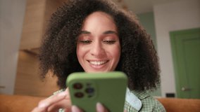 Woman Scrolling Smartphone. 20s mixed race female using smartphone sitting on couch at home. Young adult person cell phone addicted. - Powered by Shutterstock - Get 15% off with code: PIKWIZARD15