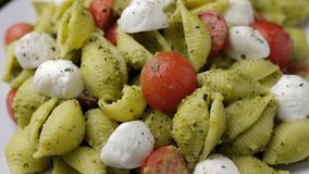 Pesto Pasta Salad with Cherry Tomatoes and Mozzarella cheese. Healthy food. Rotating video