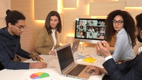 Side view of the businesspeople talking with a lot of coworkers via video call. They sitting at the office desk and using trendy computer for video meeting - Powered by Shutterstock - Get 15% off with code: PIKWIZARD15