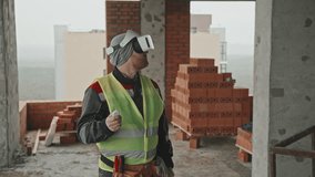Mature Caucasian foreman wearing VR headset using augmented reality at work at construction site - Powered by Shutterstock - Get 15% off with code: PIKWIZARD15