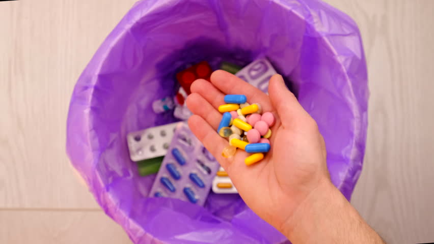 throws medicine pills into the trash.