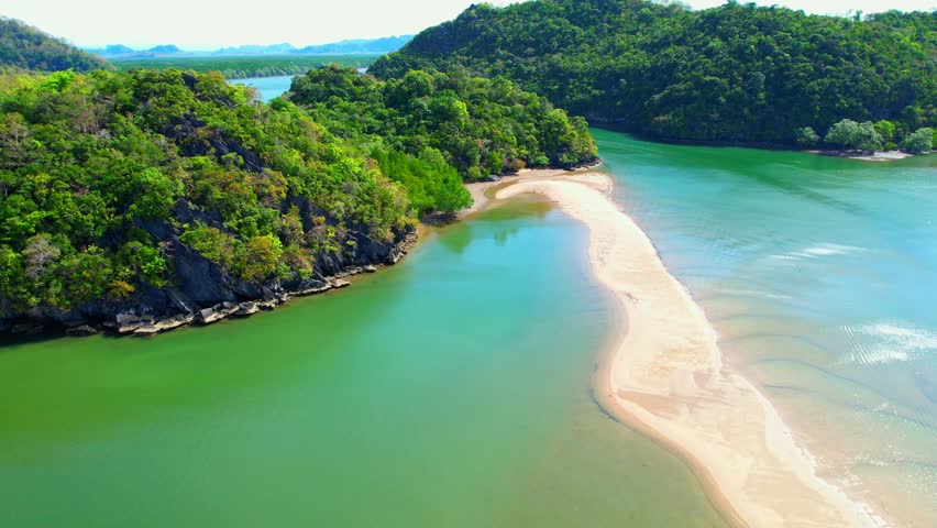 Sandbar appears as a long, narrow strip of sand that stretches out from the shore, surrounded by the crystal-clear, turquoise waters of the tropical sea. (Dragon Spine Beach, Satun Province, Thailand)