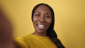 African woman having video call smiling over isolated yellow background