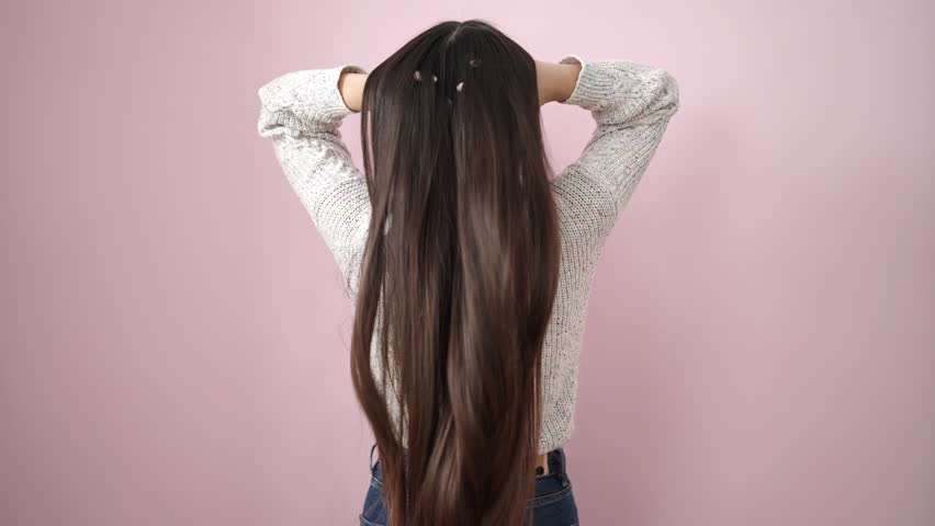 Young chinese woman combing hair with hands over isolated pink background | Shutterstock HD Video #1100742619