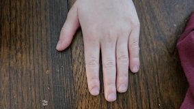 A child's hand on a table going up and down.