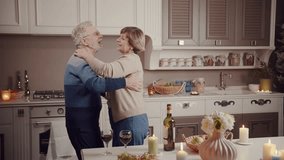 A cute elderly couple drinks wine and dances in the evening at home in the kitchen. Anniversary celebration. Grandma and grandpa. The secret of love. Love for life. - Powered by Shutterstock - Get 15% off with code: PIKWIZARD15