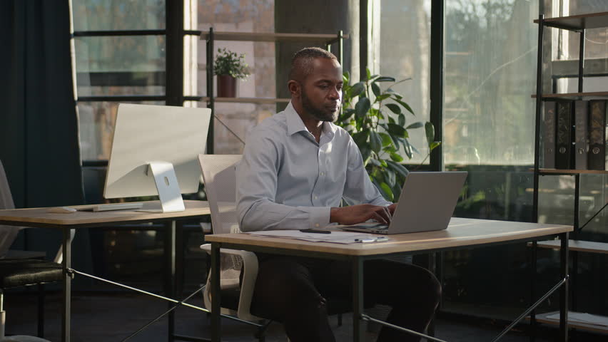 Relaxed African American mature businessman senior happy man finish computer work close laptop relaxing in sunny warm comfortable office male specialist stretch muscles put hands behind head day end Royalty-Free Stock Footage #1100745809