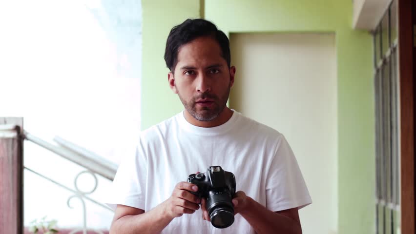 Video of male photographer indicating and taking a photo on a light background. Concept of technology, professions, lifestyles and arts.