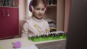 Caucasian Girl Learning to Play Xylophone, Piano. Distance Learning. Schoolgirl Studying Online Using Laptop Music Lesson. School Student Wearing Headphones Watching Internet Video Music Course. 