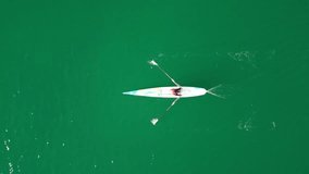 Aerial drone bird's eye view video of sport canoe operated by young woman in emerald clear waters
