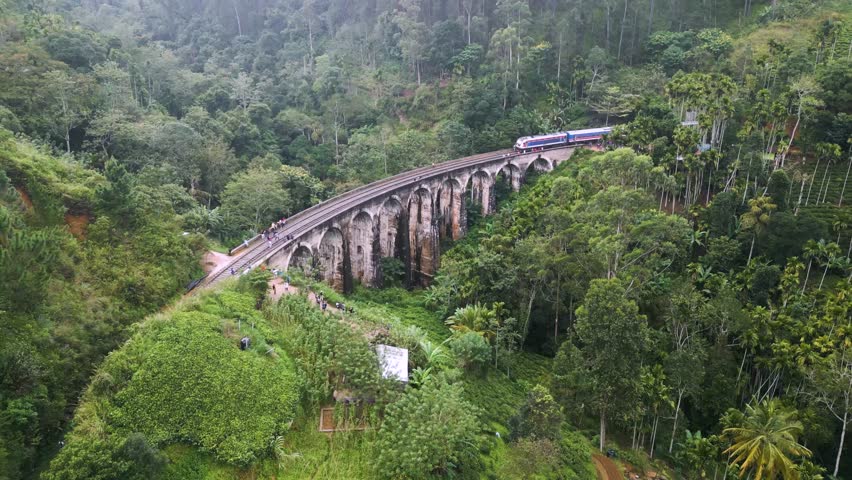 A train runs on Nine Arches Bridge in Sri Lanka, in the middle of a lush jungle Royalty-Free Stock Footage #1100751601