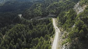 Drone Video Following car high altitude mountain winding road wide shot pine forest Gramos