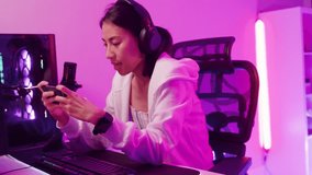 Happy asia female gamer wear headphone competition play video game online with smartphone share experience with audience neon light at night. Esport streaming game online, cybersport luiser activity.