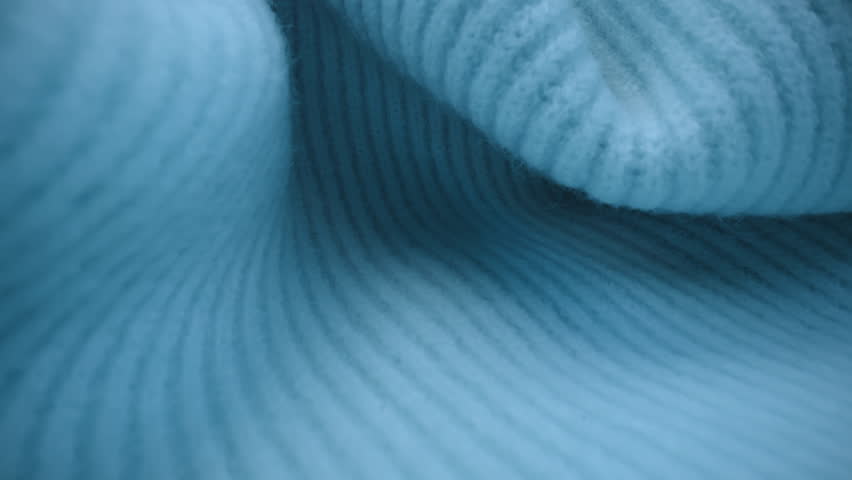 Macro shot wool fabric, knitted wool pullover. Slider dolly extreme close-up clothing material blue woollens, wool fibers. Laowa lens camera glides over warm winter clothing fabric texture