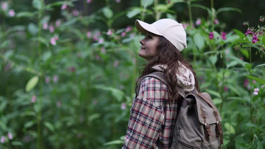 Young Caucasian woman with backpack traveling in the forest. The girl is feeling fresh, wonderful exciting and relax in nature wild. slow motion | Shutterstock HD Video #1100767555