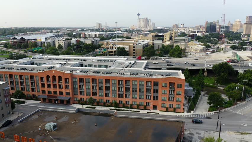San Antonio Pearl District aerial orbit of downtown, pan left looking at apartment complex and freeway commuters near riverwalk in 4k