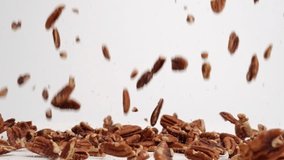 Pecan nut pieces raining down onto white table top and bouncing into a pile in slow motion - Powered by Shutterstock - Get 15% off with code: PIKWIZARD15