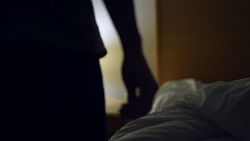 Man laying down in bed to rest after long day. Person going to sleep going under bedsheets resting turning bedside lamp off Royalty-Free Stock Footage #1100778473