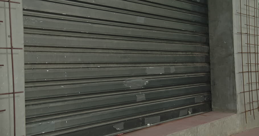 Female Entrepreneur opening front door of small business flower shop. Open for business concept. Sliding garage door shop store.