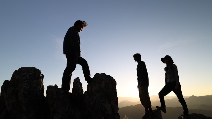 Silhouette of helping hands during climbers A man helps a man climb a steep rock and has people helping and teamwork concept. Shadow on the mountain with sunlight. Success on the cliff. | Shutterstock HD Video #1100784897