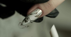 pasting a pattern on a nail in a beauty salon. the master does a manicure. vertical video