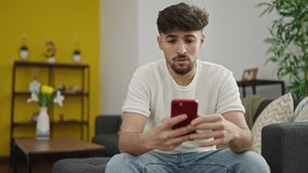 Young arab man using smartphone with worried expression at home