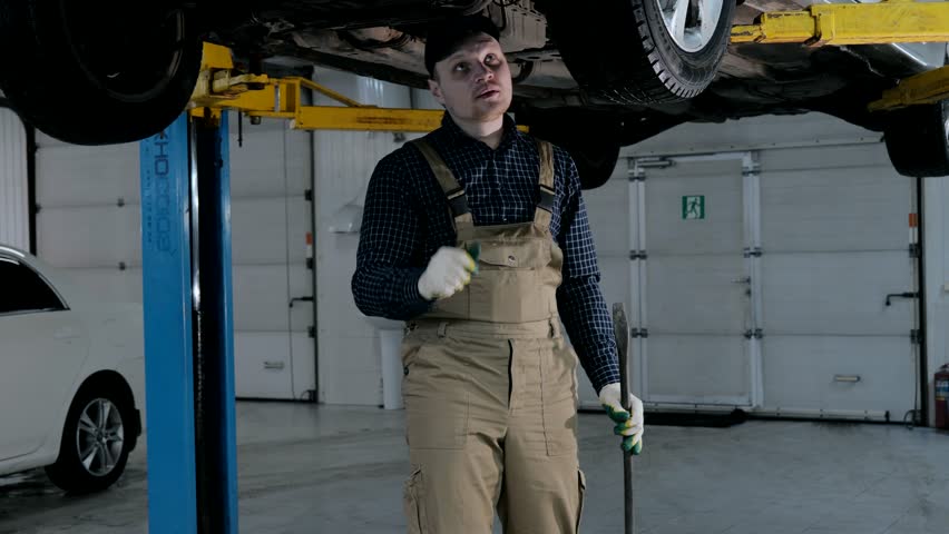 Auto mechanic inspects car suspension, car suspension diagnostics. Male mechanic inspecting a car | Shutterstock HD Video #1100791299
