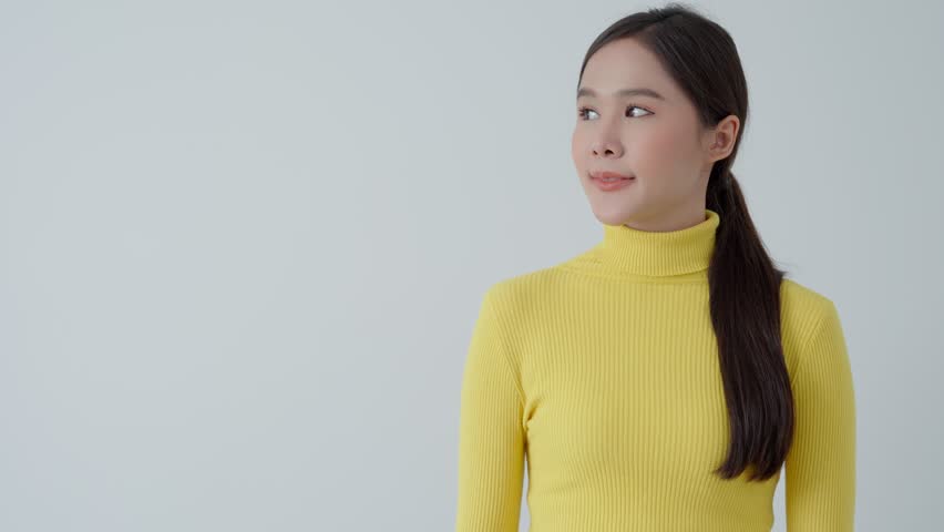 Portrait asian beautiful girl pointing blank space isolated background. Happy woman pointing on something. young female standing pointing finger sideways, billboard, introduction, advertisement, space