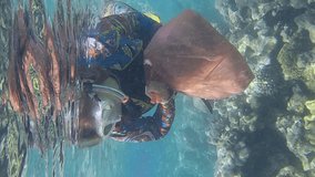 VERTICAL VIDEO, Woman in diving equipment swims and collects plastic debris underwater on bottom of coral reef. Snorkeler cleaning Ocean from plastic pollution. Plastic pollution of the Ocean