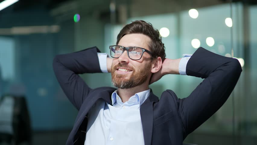 Resting entrepreneur investor with hands behind head feels satisfied with work well done indoor Calm bearded businessman relax after hard working day finished project job on computer at modern office | Shutterstock HD Video #1100795905