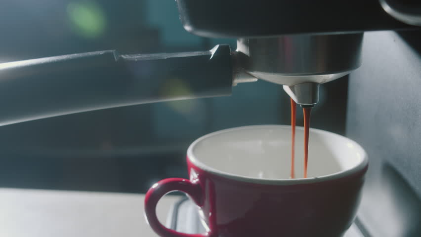 Pouring coffee stream from machine in red cup. Home making hot Espresso. Using filter holder. Flowing fresh ground coffee. Drinking roasted black coffee in the morning.breakfast. Coffee break. 4K | Shutterstock HD Video #1100799119