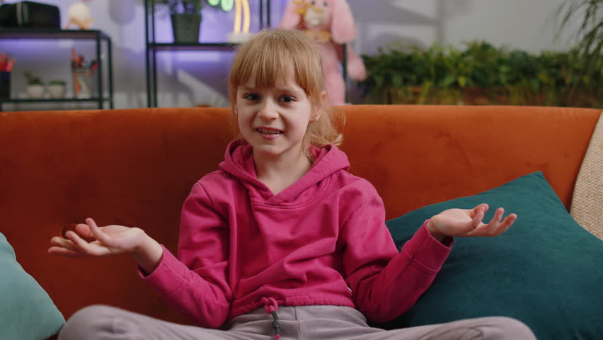 What. Why. Young child kid girl raising hands in indignant expression, asking reason of failure, demonstrating disbelief irritation by troubles. Female teen toddler at home in living room sits on sofa | Shutterstock HD Video #1100803091