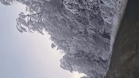 vertical video. winter snow-covered road in a mountain forest. shooting through the windshield of the car. travel by car. the concept of the beauty of nature. Safe driving on slippery roads.
