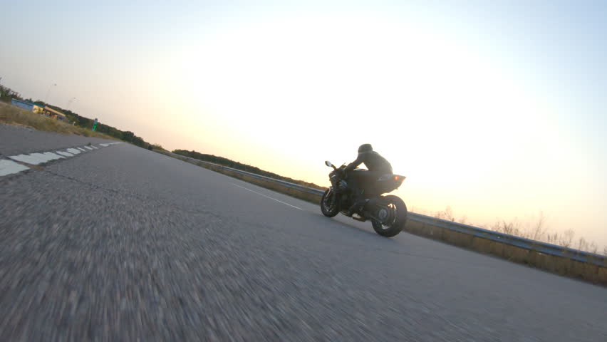 Follow to biker riding on modern sport motorbike on country road at sunset. Motorcyclist racing his motorcycle at highway. Guy driving bike during trip. Concept of journey and freedom. Aerial shot | Shutterstock HD Video #1100806593